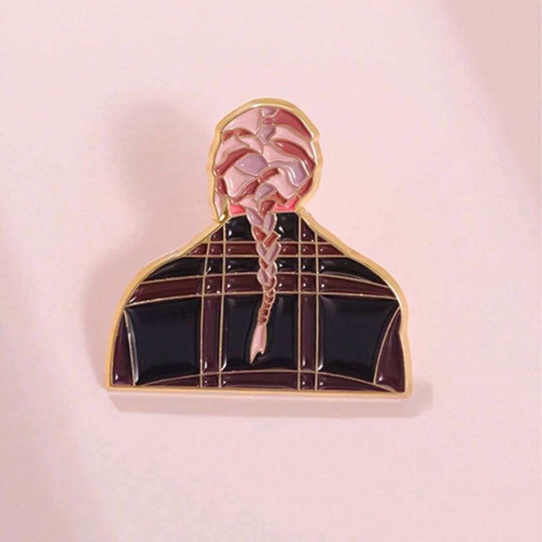 An enamel pin featuring the album cover of Taylor Swift's Evermore, with a pink background and a stylized depiction of Taylor Swift's character and hair.
