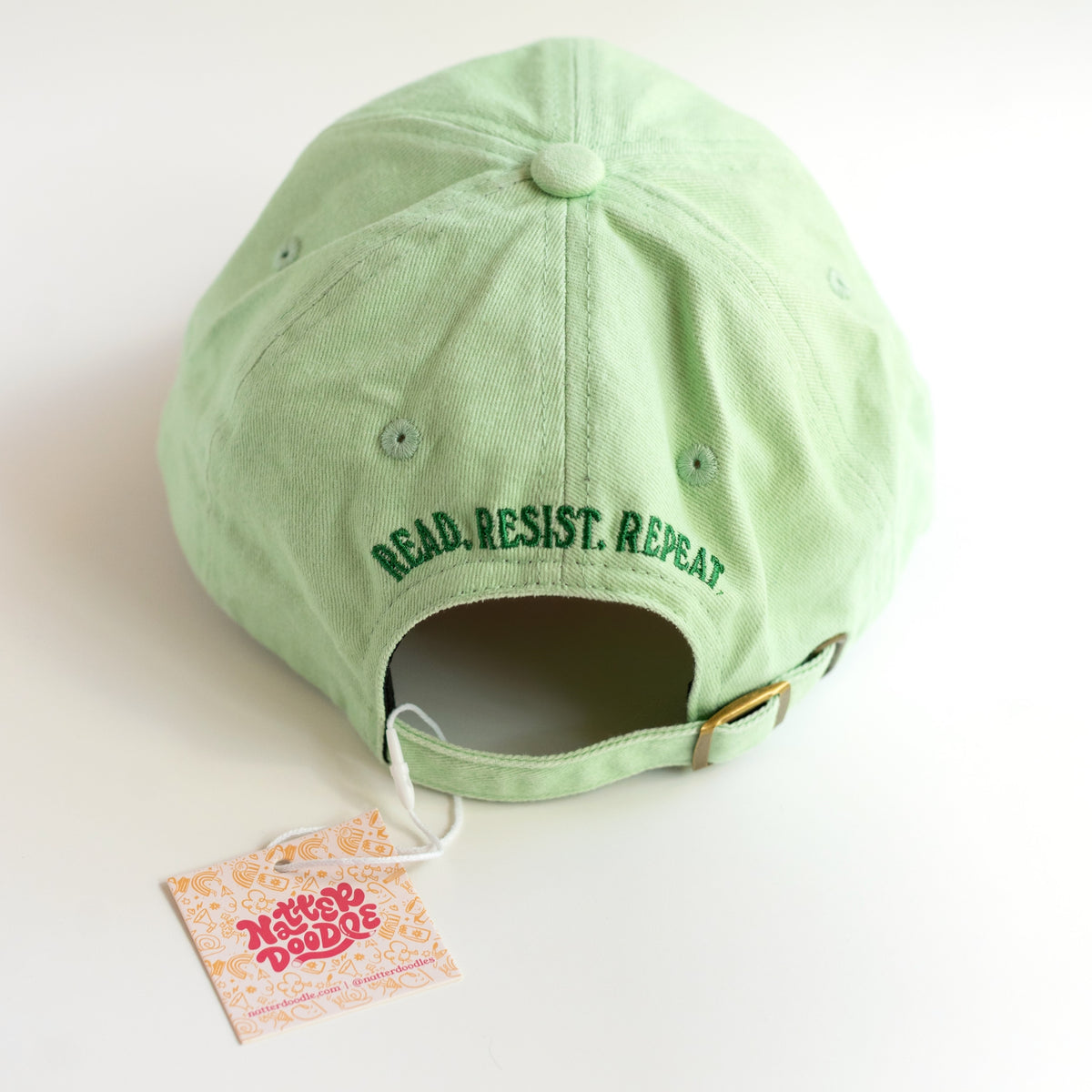 Back of the dad cap with Read. Resist. Repeat. embroidery and gold-tone metal clasp