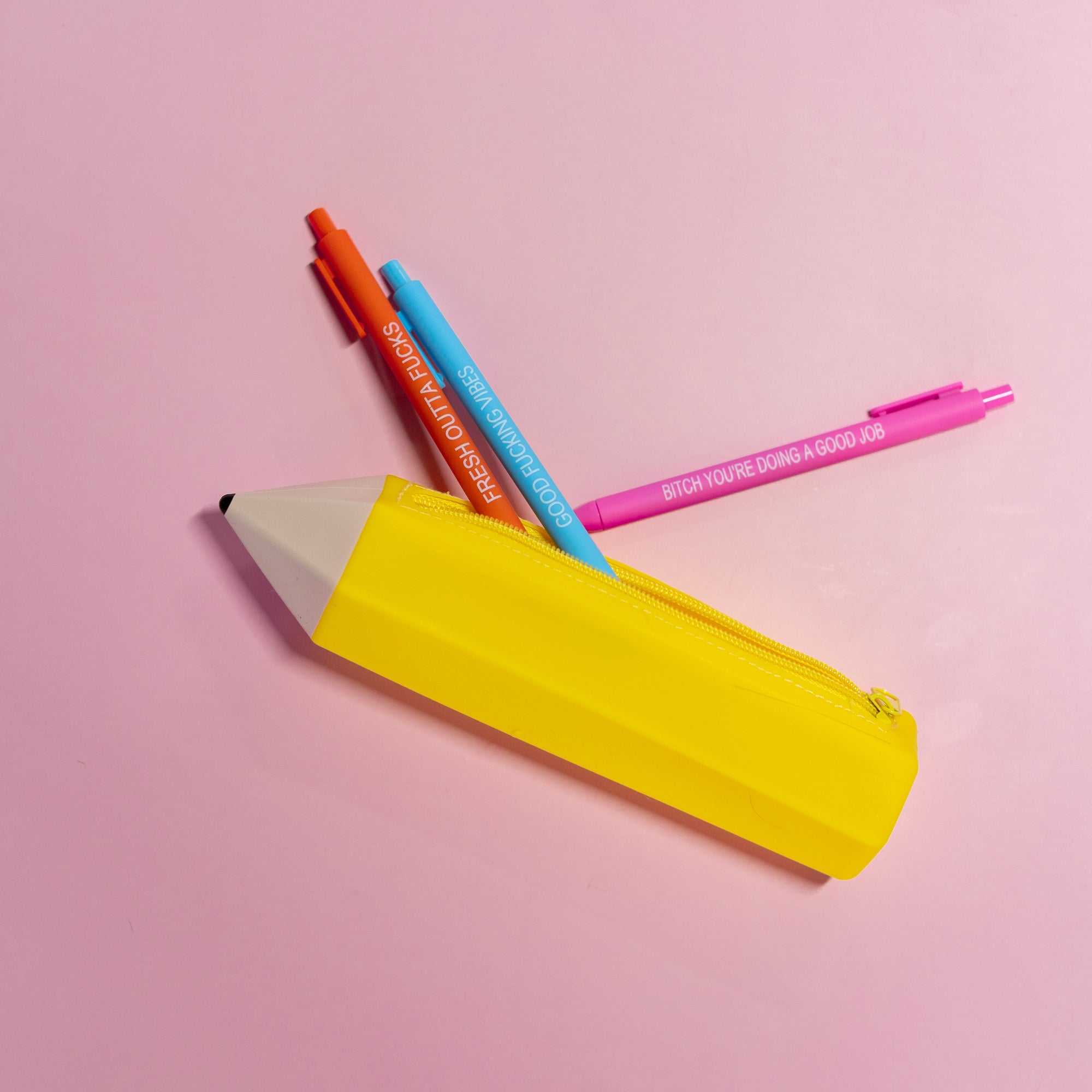Colorful pens and a yellow pencil sharpener on a pink background