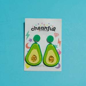 Avocado-shaped earrings on a 'cheerful' branded card against a blue background