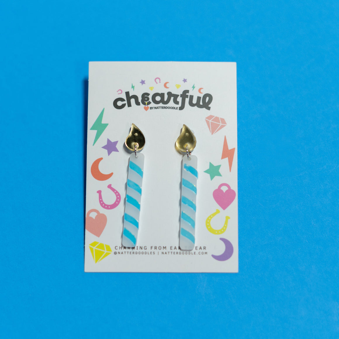 Pair of earrings on a 'chearful' branded card against a blue background