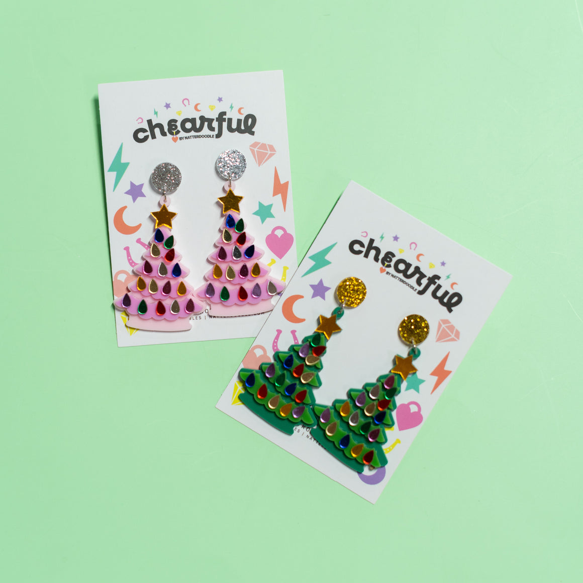 Two packages of 'cheerful' earrings on a green background