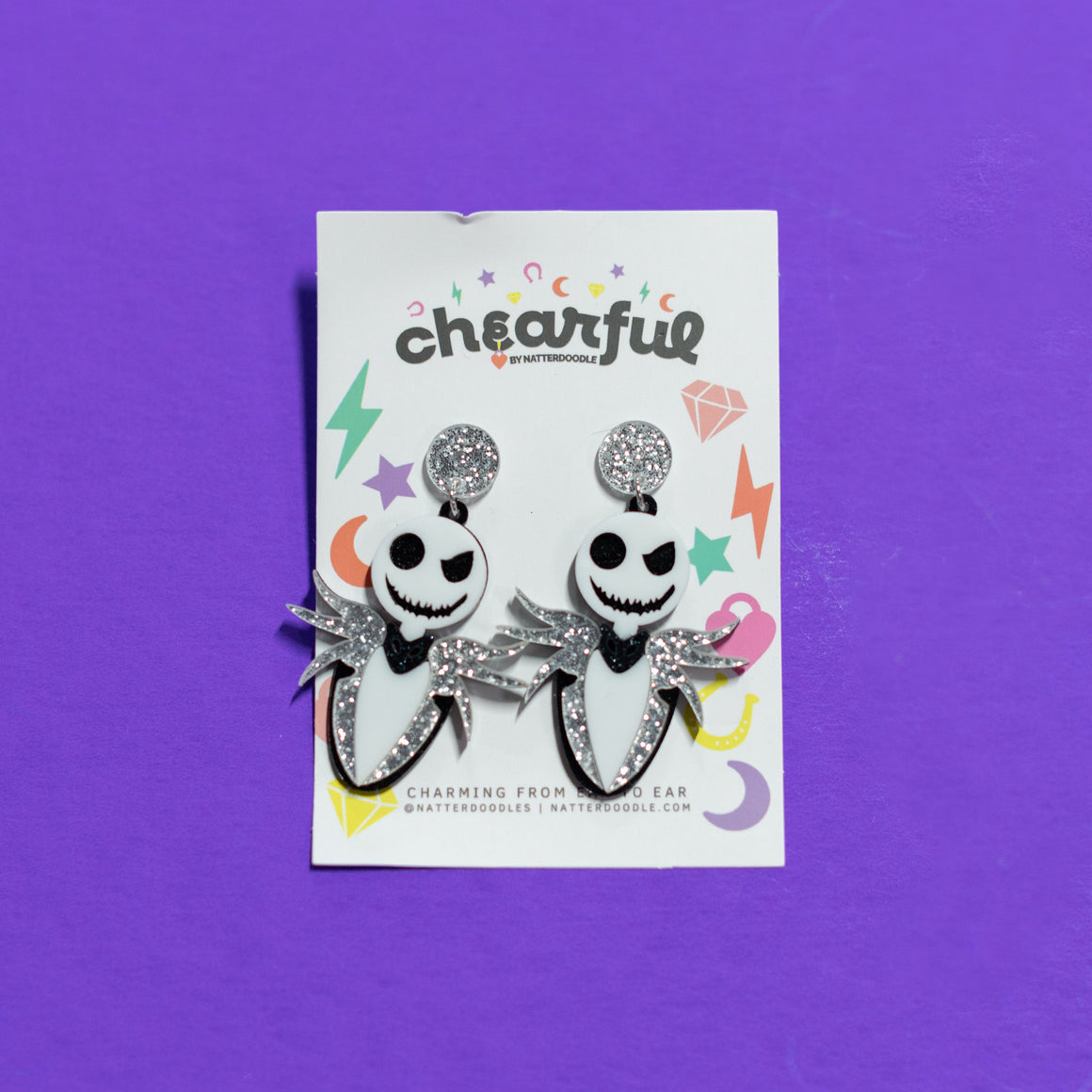 Pair of earrings with a 'cheerful' label on a purple background