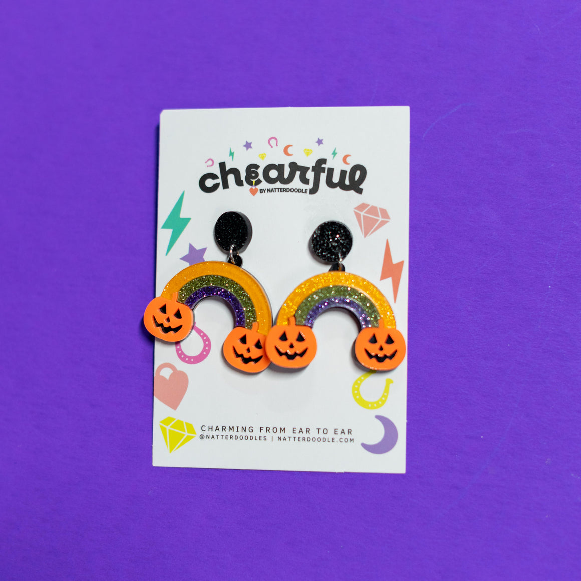 Halloween-themed earrings on a 'chearful' branded card against a purple background