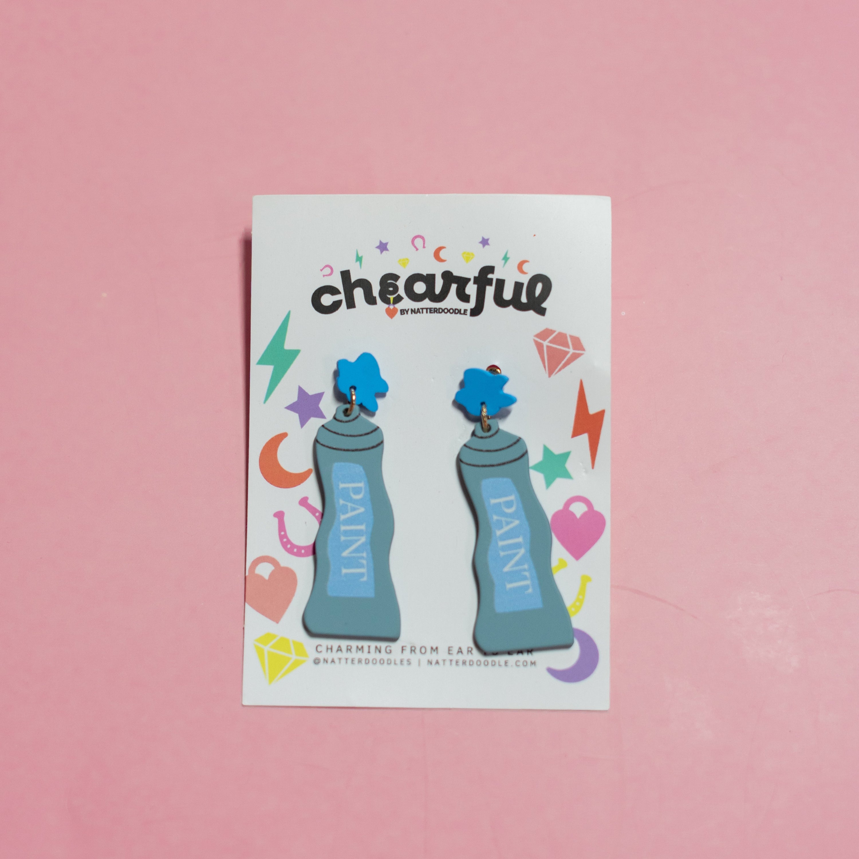 Pair of blue earrings with blue paint cans on a 'cheerful' branded card against a pink background
