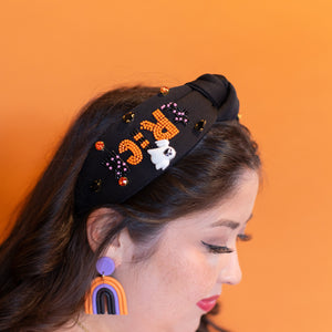Woman wearing a decorative headband with colorful text and graphics against an orange background