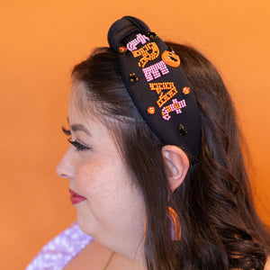 Woman wearing a decorative headband with colorful designs against an orange background