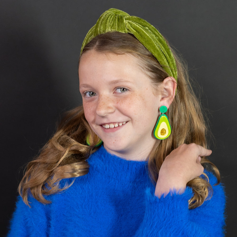 Avocado-shaped earrings on a 'cheerful' branded card against a blue background