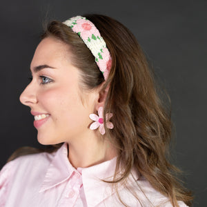 Woman wearing a floral headband and matching earrings against a dark background