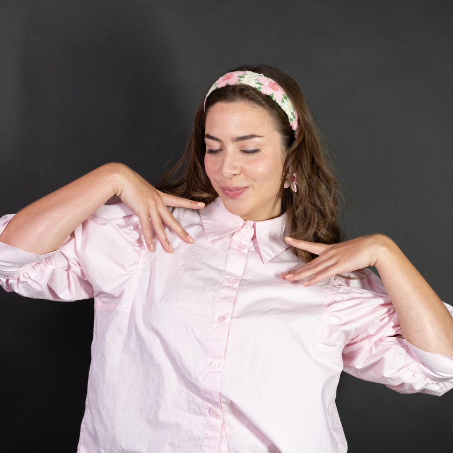 Woman wearing a floral headband and matching earrings against a dark background