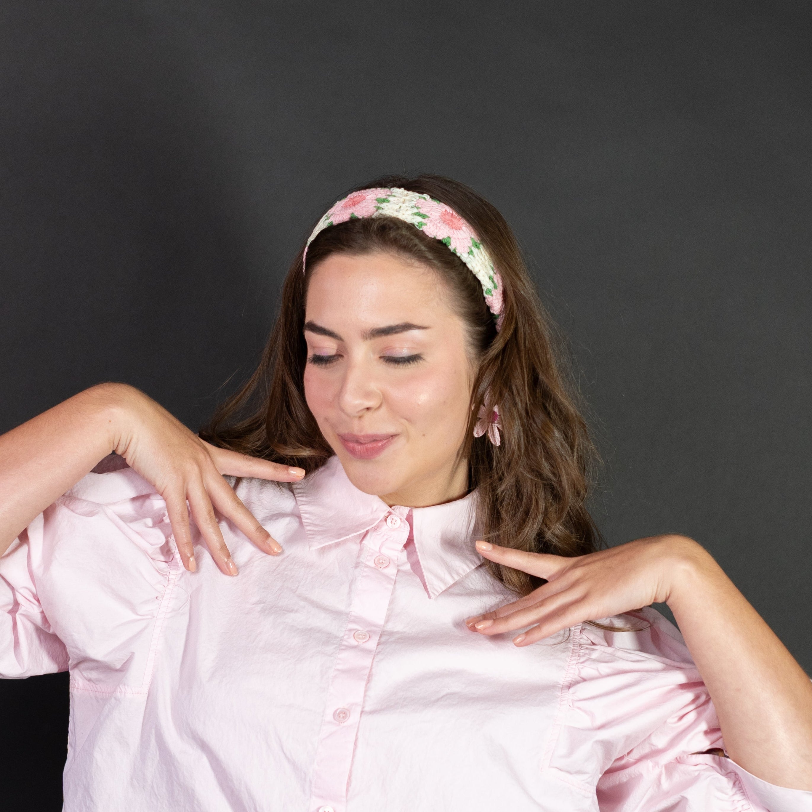 Woman wearing a pink shirt and colorful pants against a black background