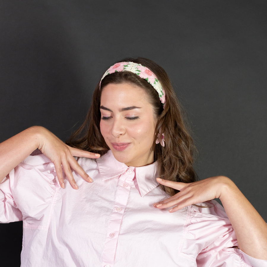 Woman wearing a floral headband and matching earrings against a dark background
