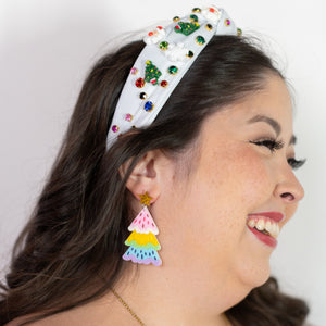 Woman wearing a colorful headband, earrings, and necklace against a white background