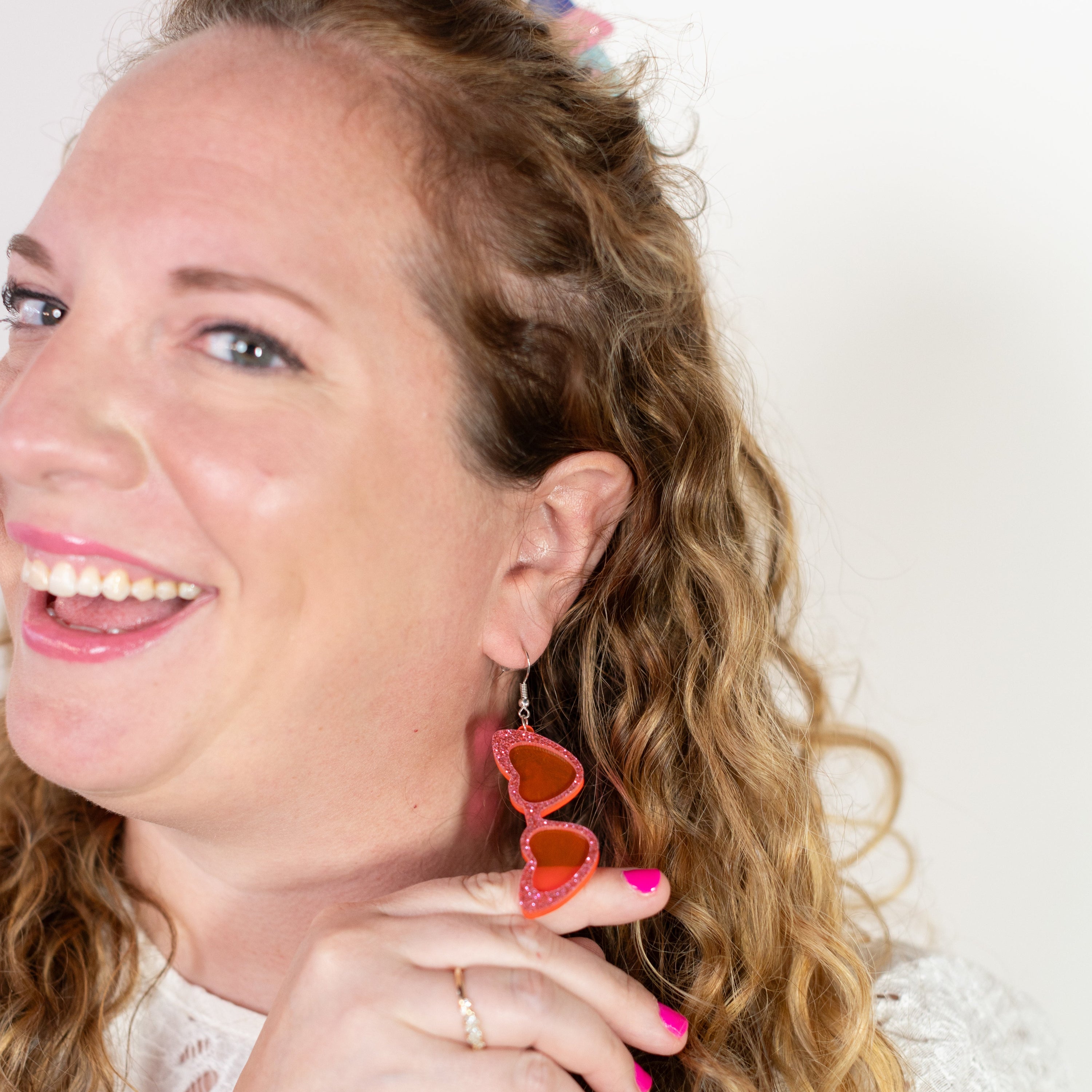 Woman wearing heart-shaped earrings with a plain background