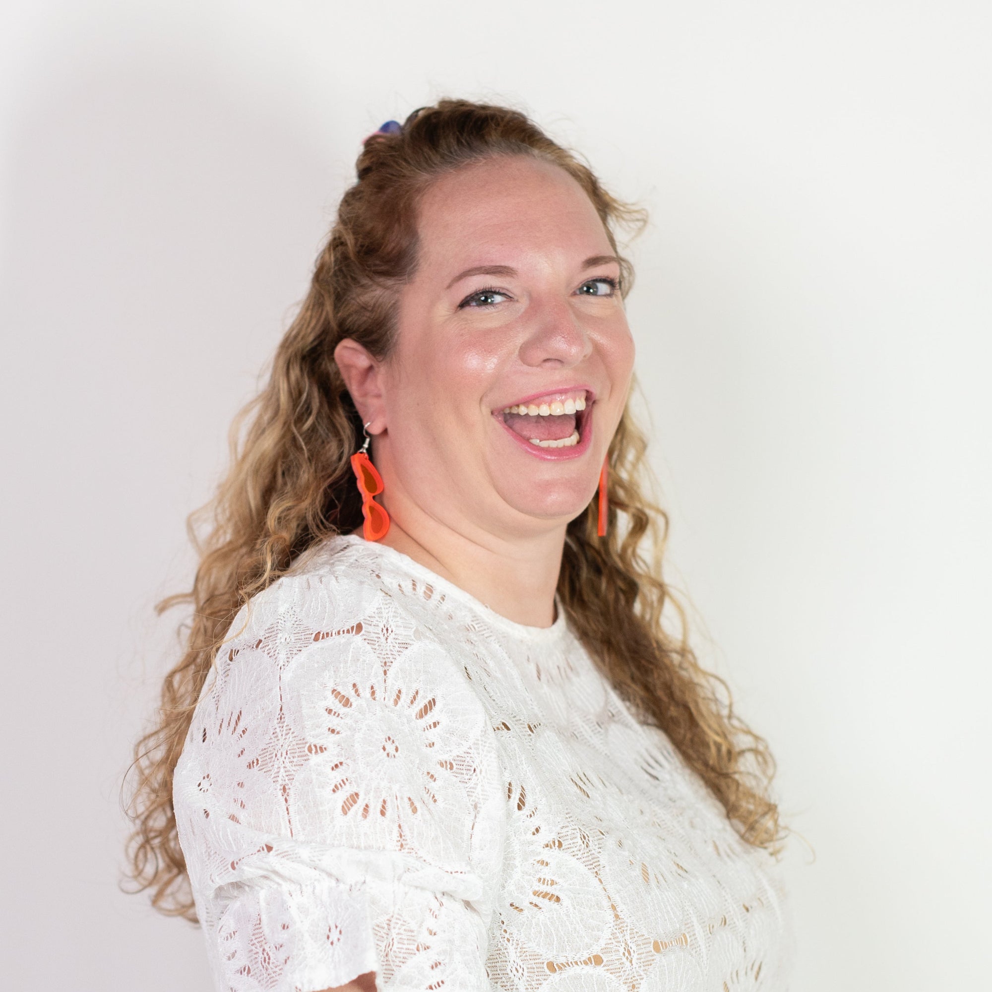 Woman wearing a white lace top against a plain background