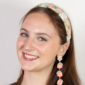 Woman wearing a black top and floral headband with earrings on a white background