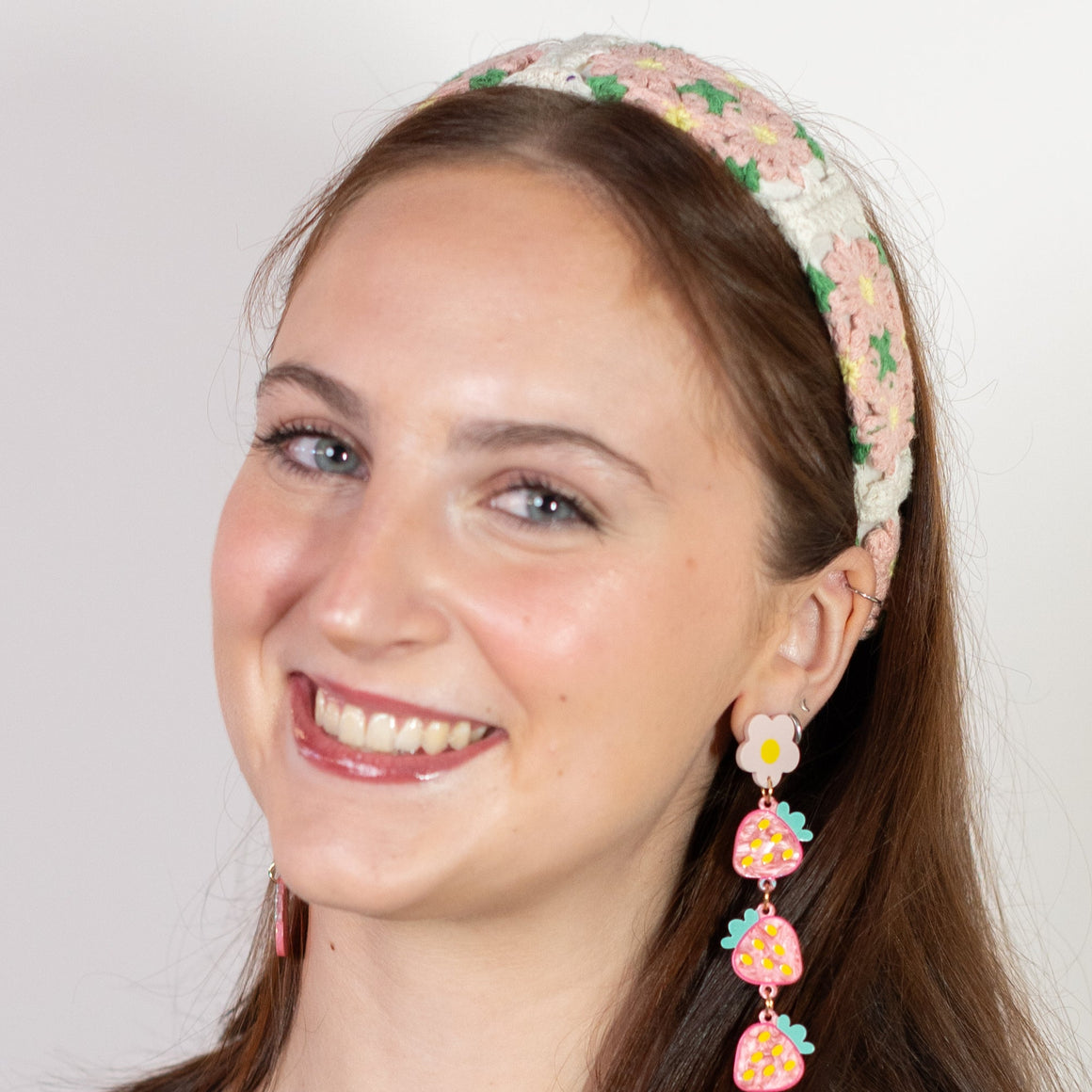 Woman wearing a black top and floral headband with earrings on a white background