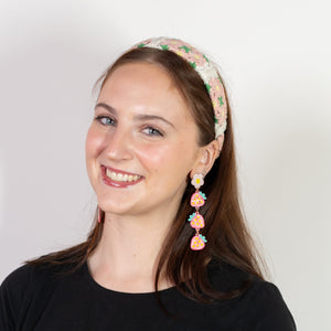 Woman wearing a black top and floral headband with earrings on a white background