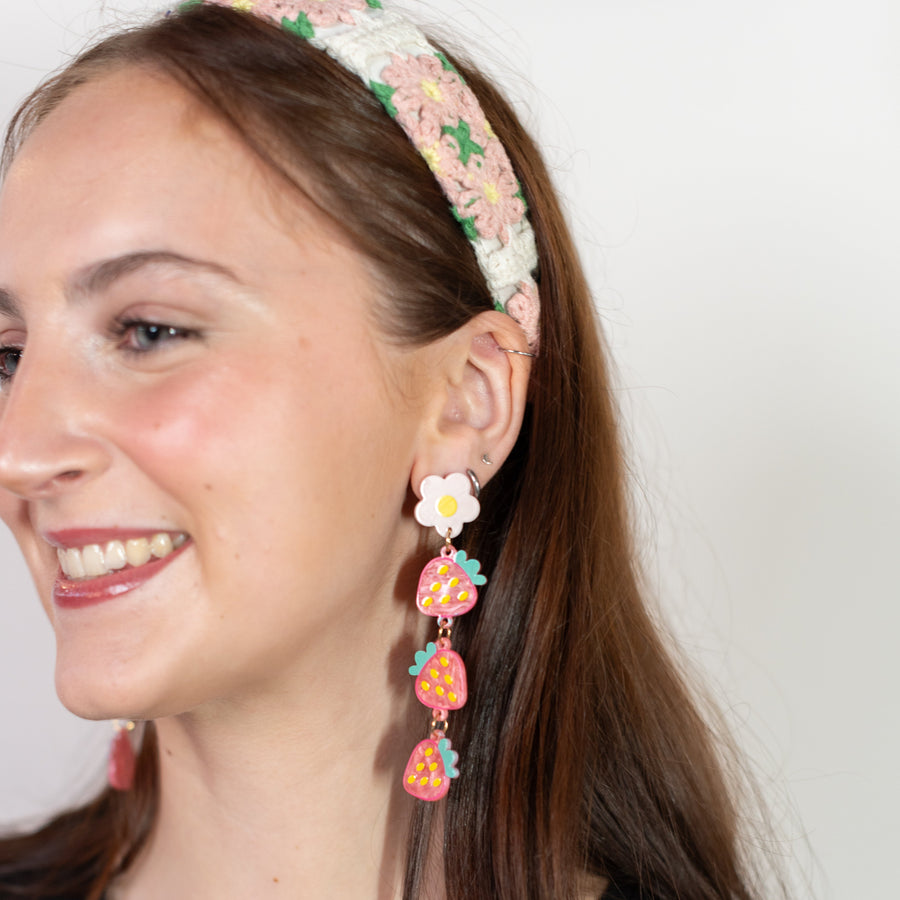 Woman wearing a black top and floral headband with earrings on a white background