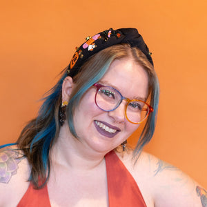 Person wearing a red dress and floral headband against an orange background