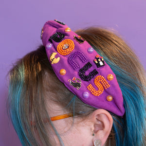 Person wearing a colorful headband with Halloween-themed decorations against a purple background
