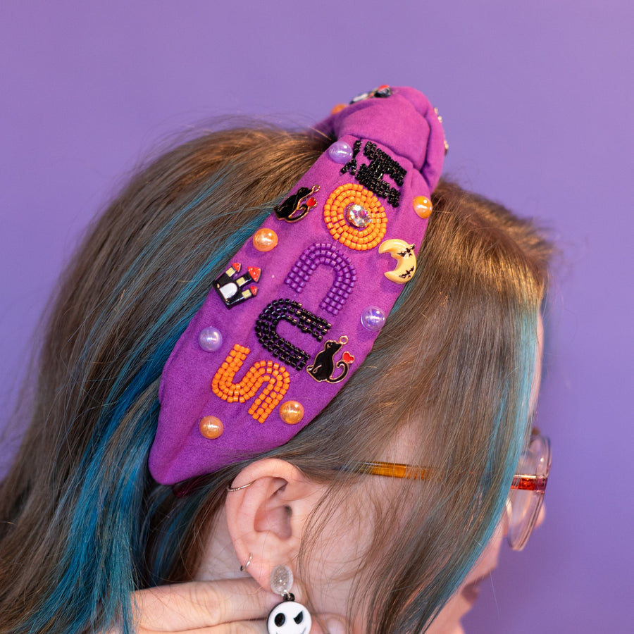 Person wearing a colorful headband with Halloween-themed decorations against a purple background