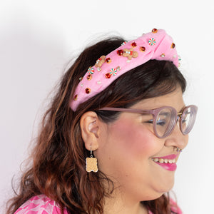Person wearing a pink headband with decorative elements on a white background