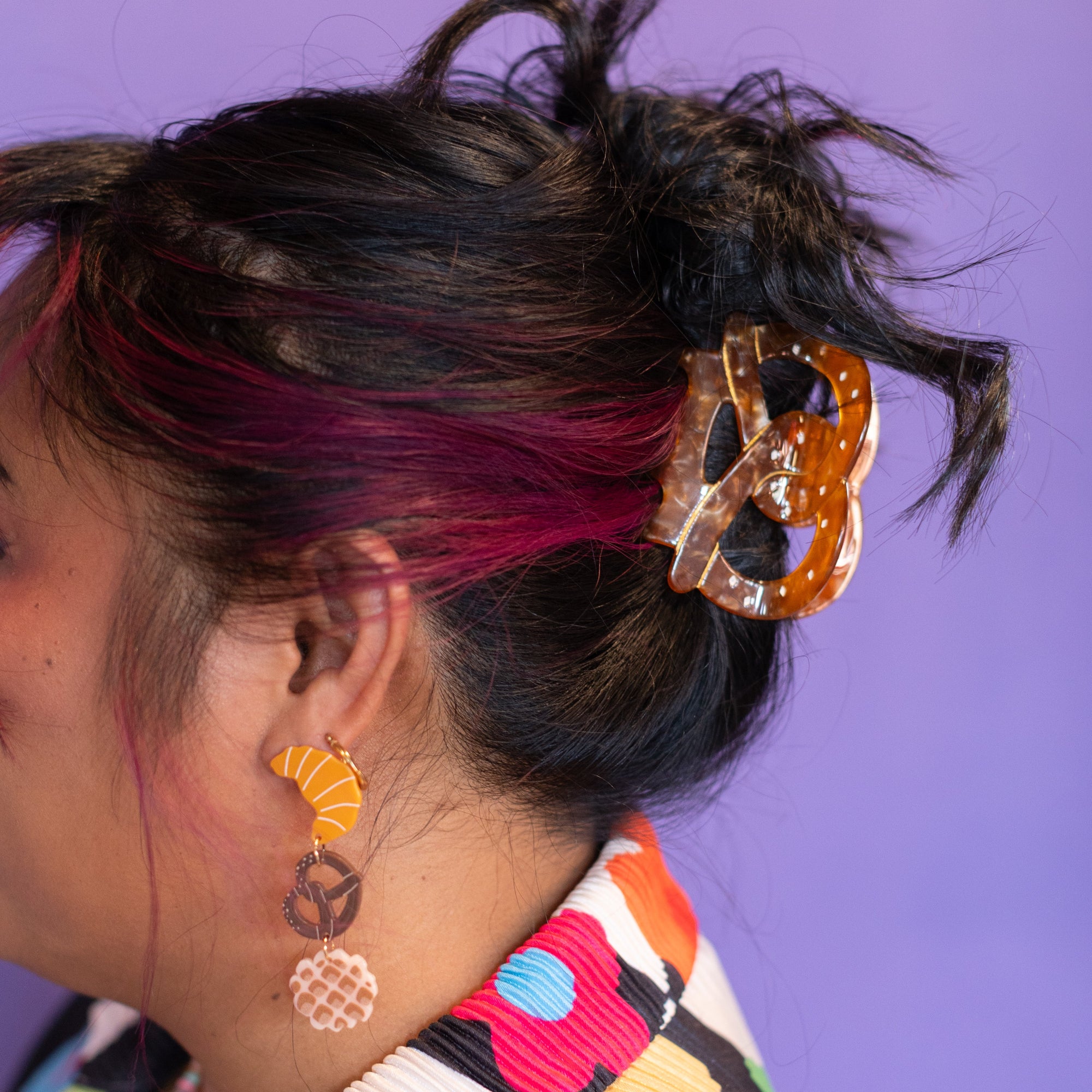 Person with colorful hair and accessories against a purple background
