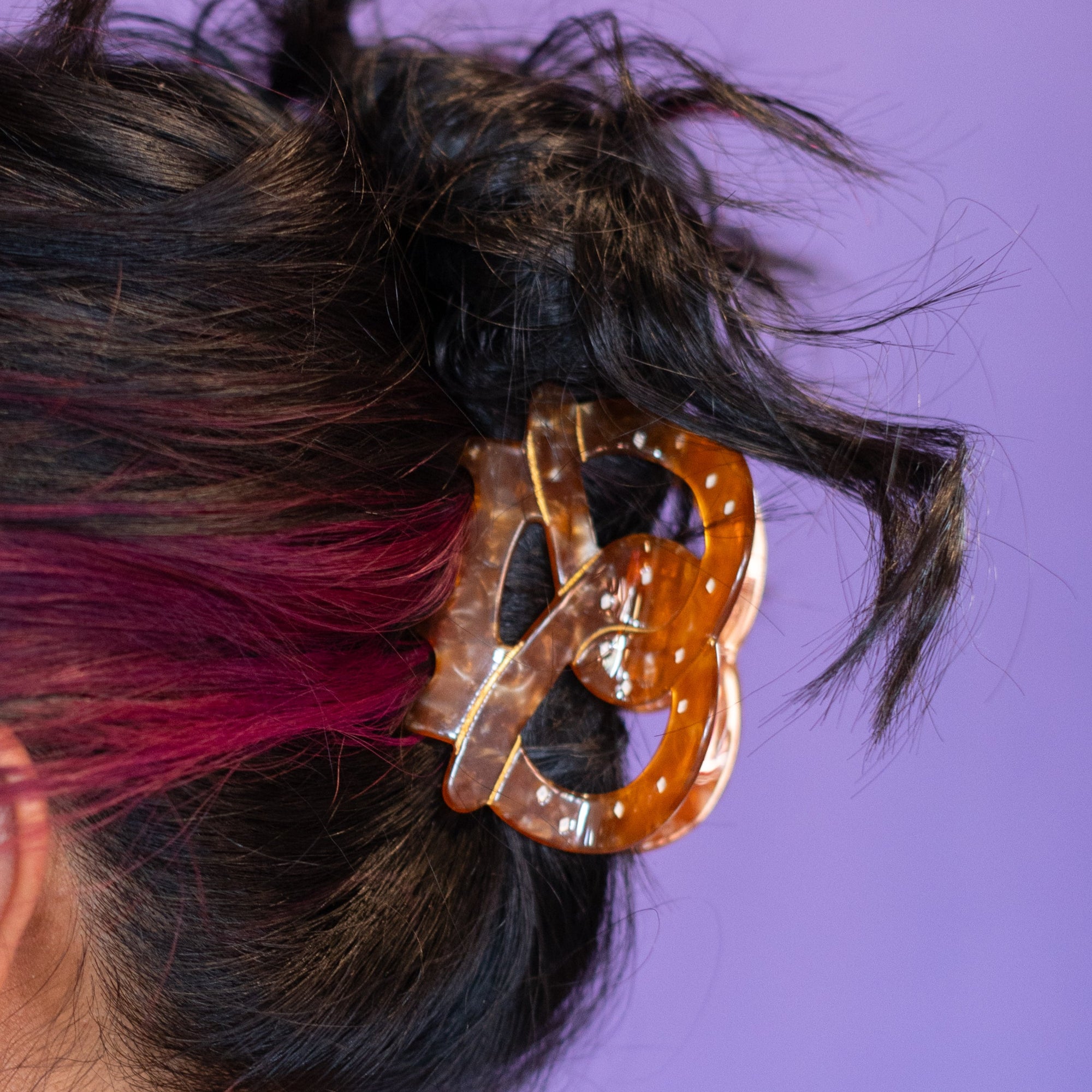 Person with colorful hair and accessories against a purple background