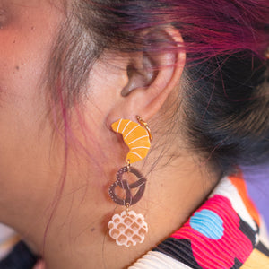 Close-up of a person wearing colorful earrings with a vibrant background