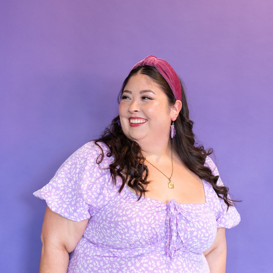 Woman wearing a purple dress and headband against a purple background