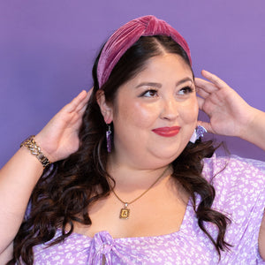 Woman wearing a purple dress and headband against a purple background