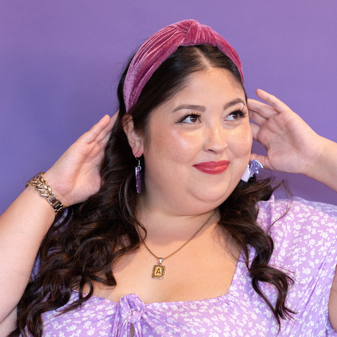 Woman wearing a purple dress and headband against a purple background