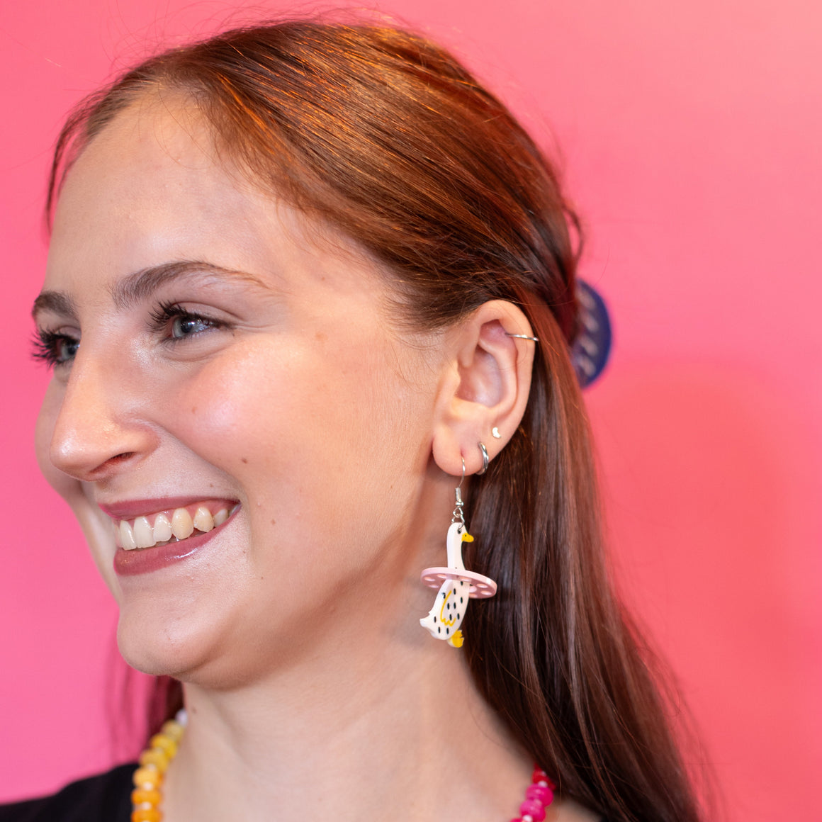 Woman wearing colorful jewelry against a pink background
