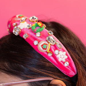Person wearing a pink headband with colorful embellishments against a pink background