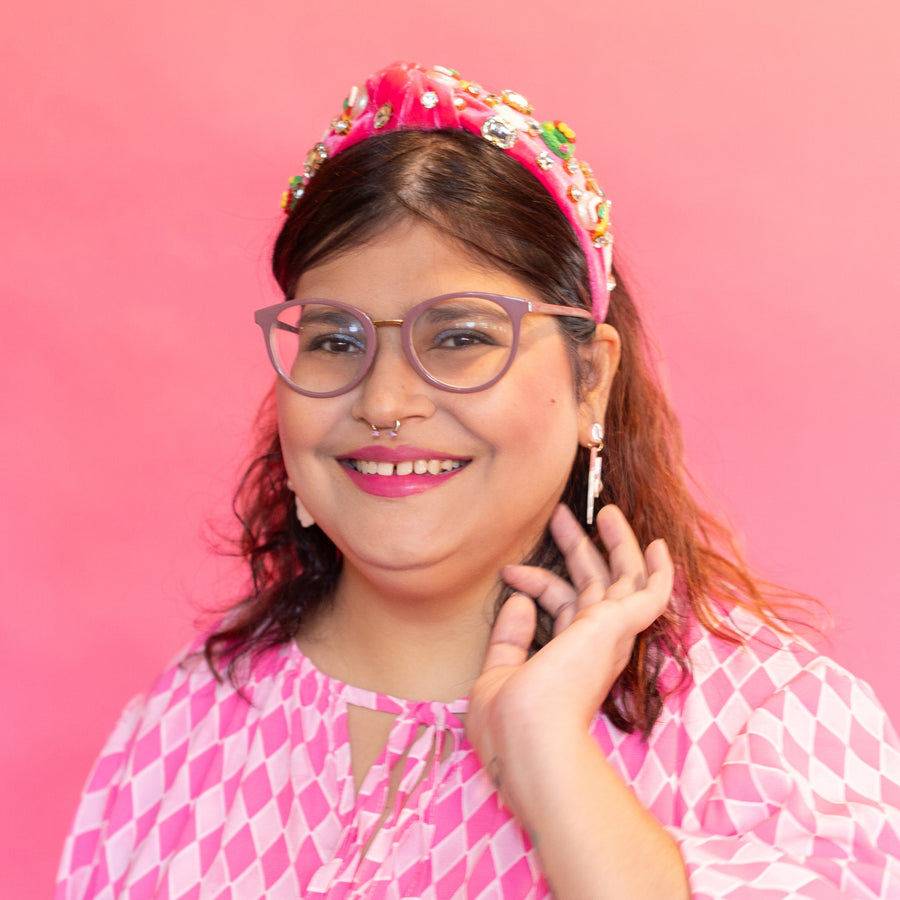 Person wearing a pink headband with colorful embellishments against a pink background