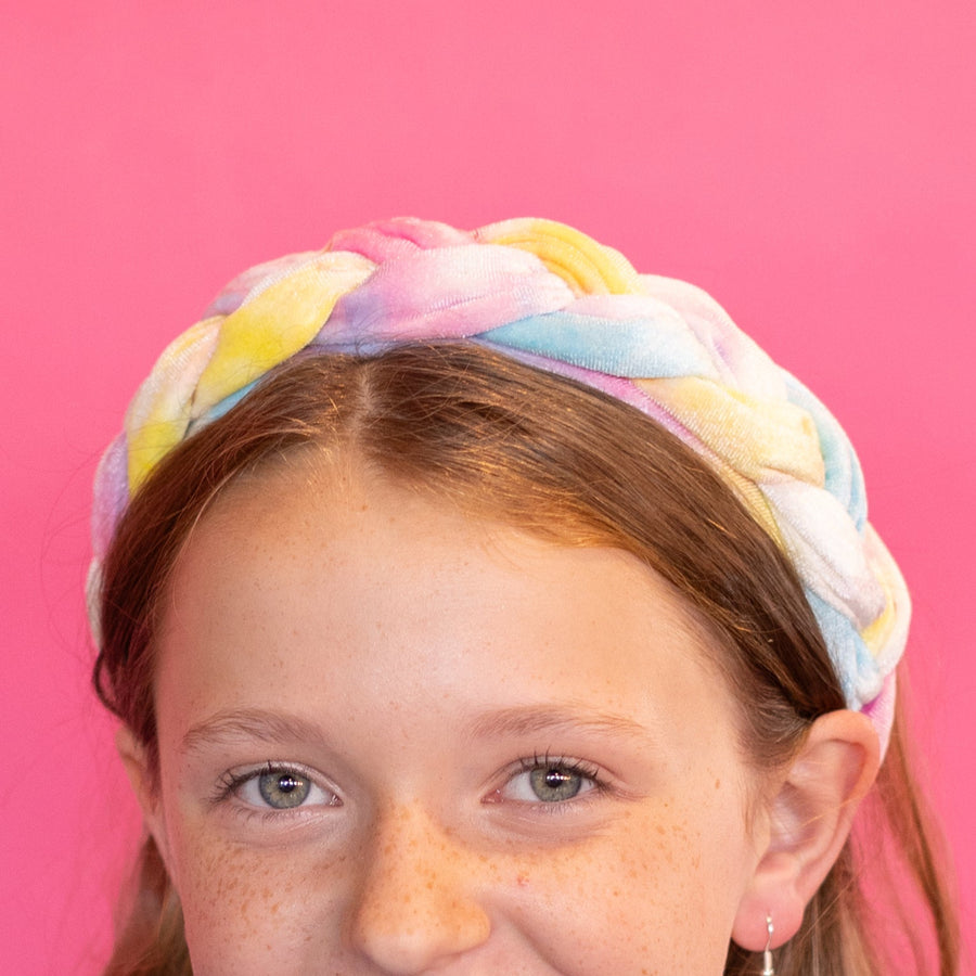 Young girl wearing a blue sweater and white skirt against a pink background
