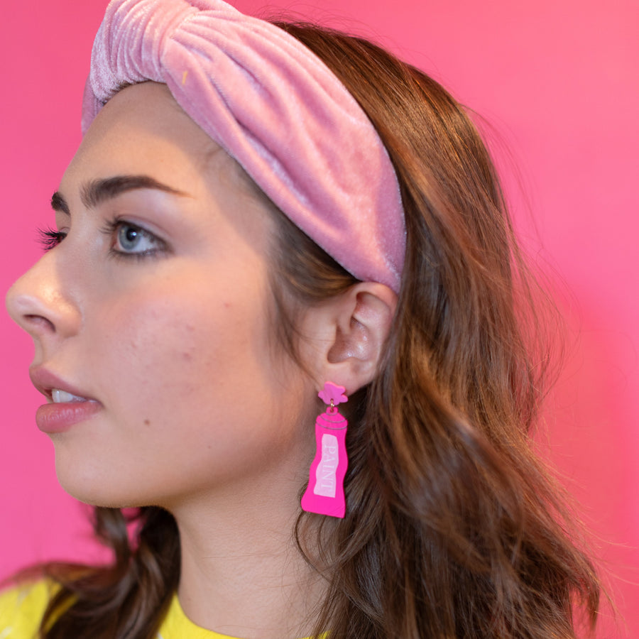 Woman wearing a yellow shirt and colorful pants against a pink background