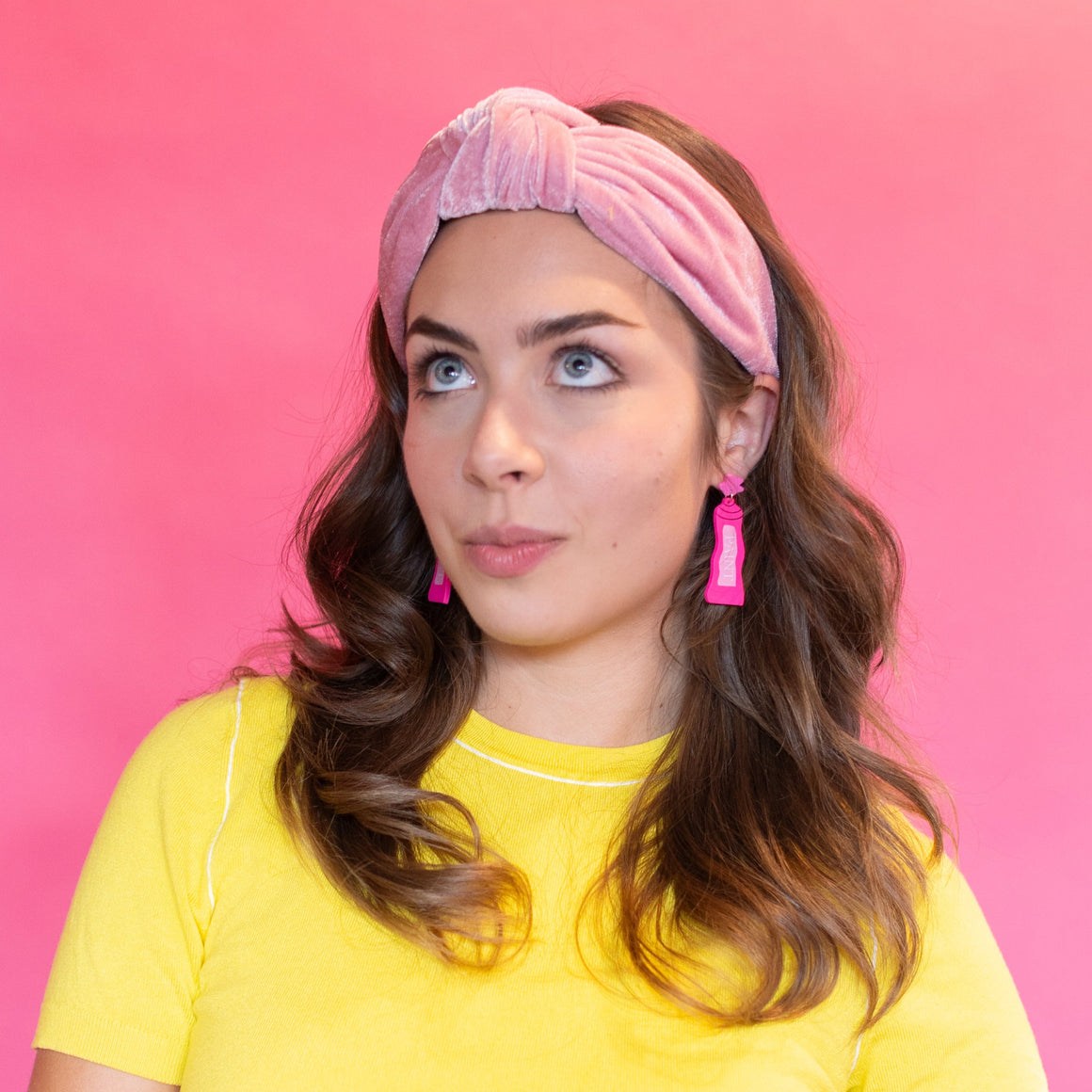 Woman wearing a yellow shirt and colorful pants against a pink background
