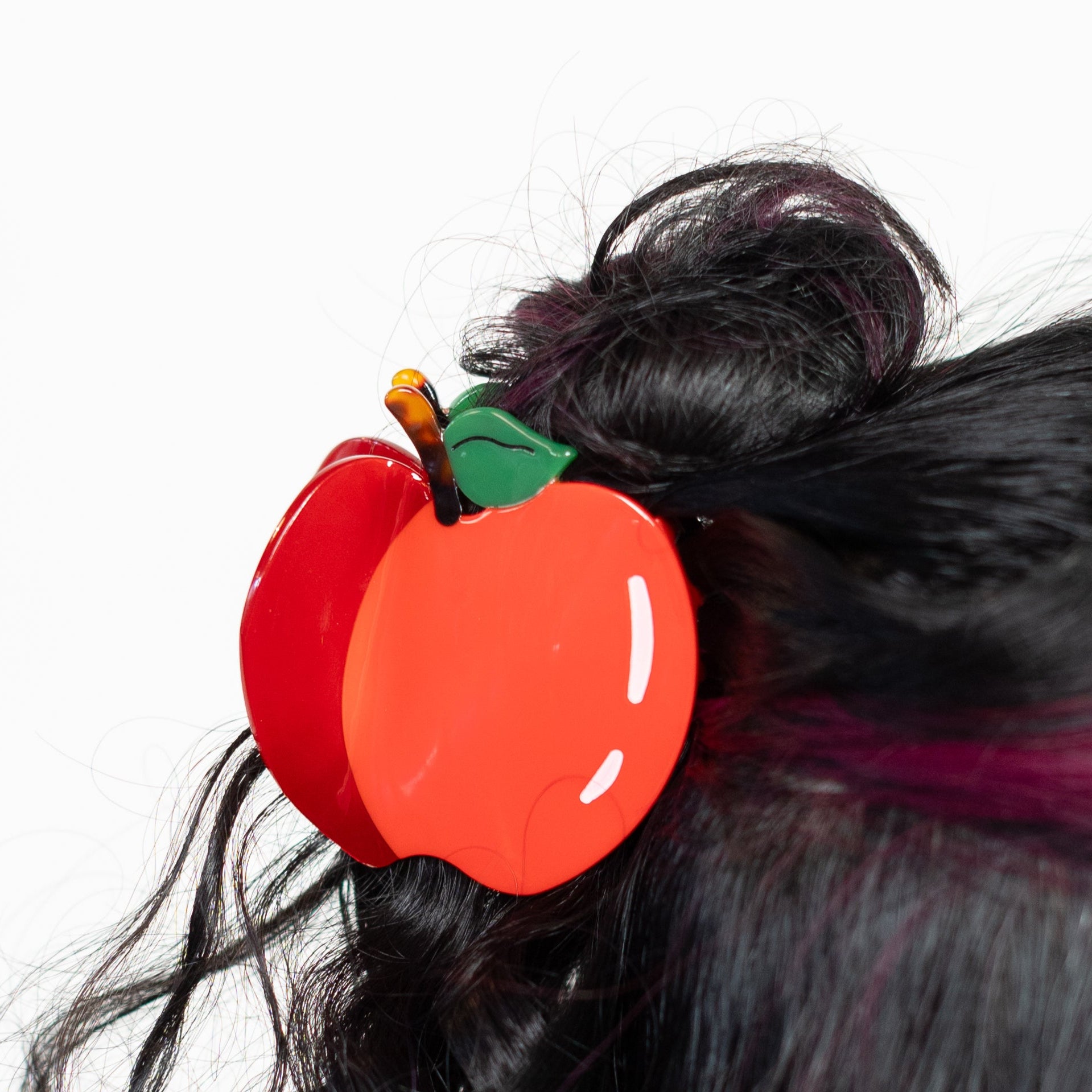Person with styled hair featuring a red apple hair clip on a white background