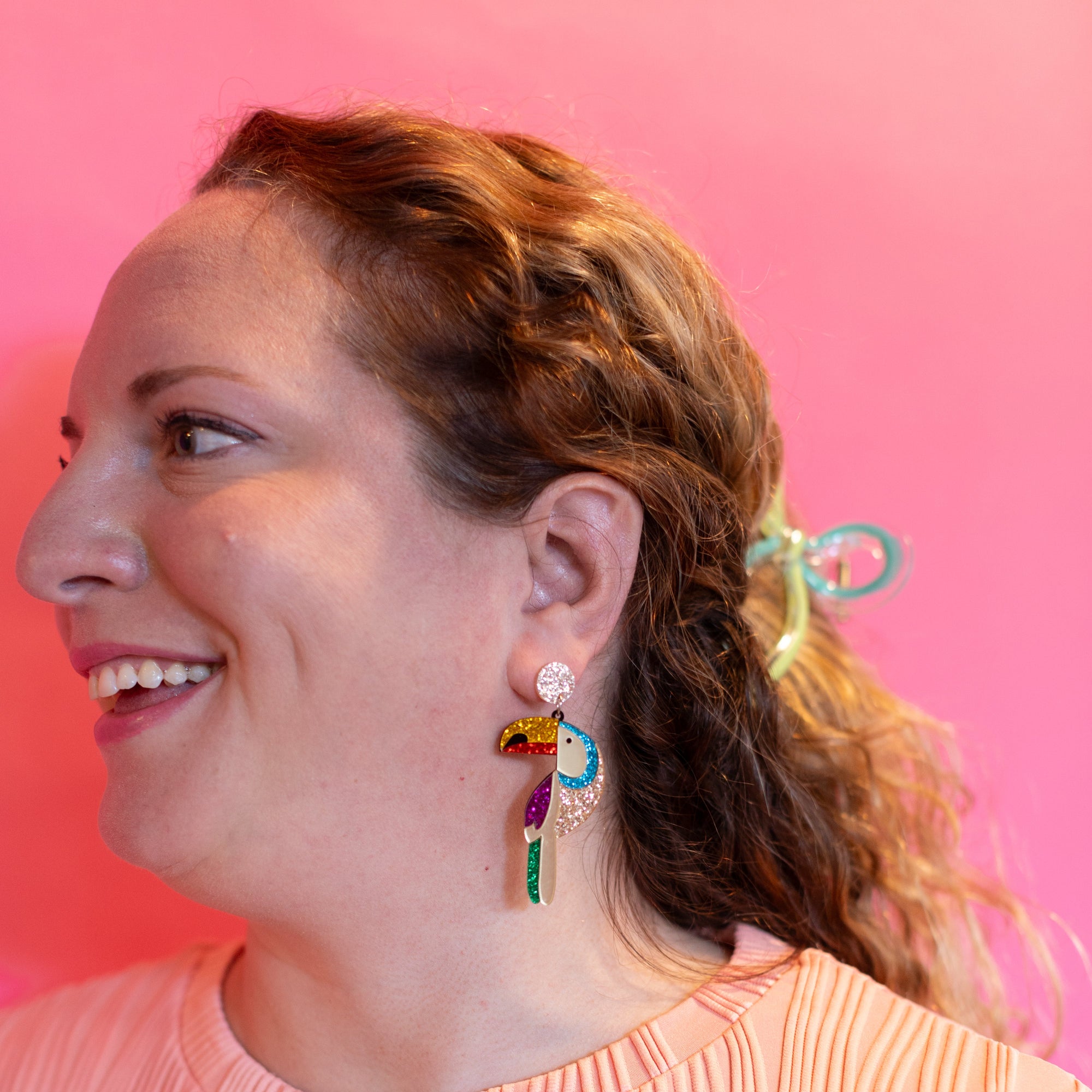 Woman wearing colorful earrings against a pink background