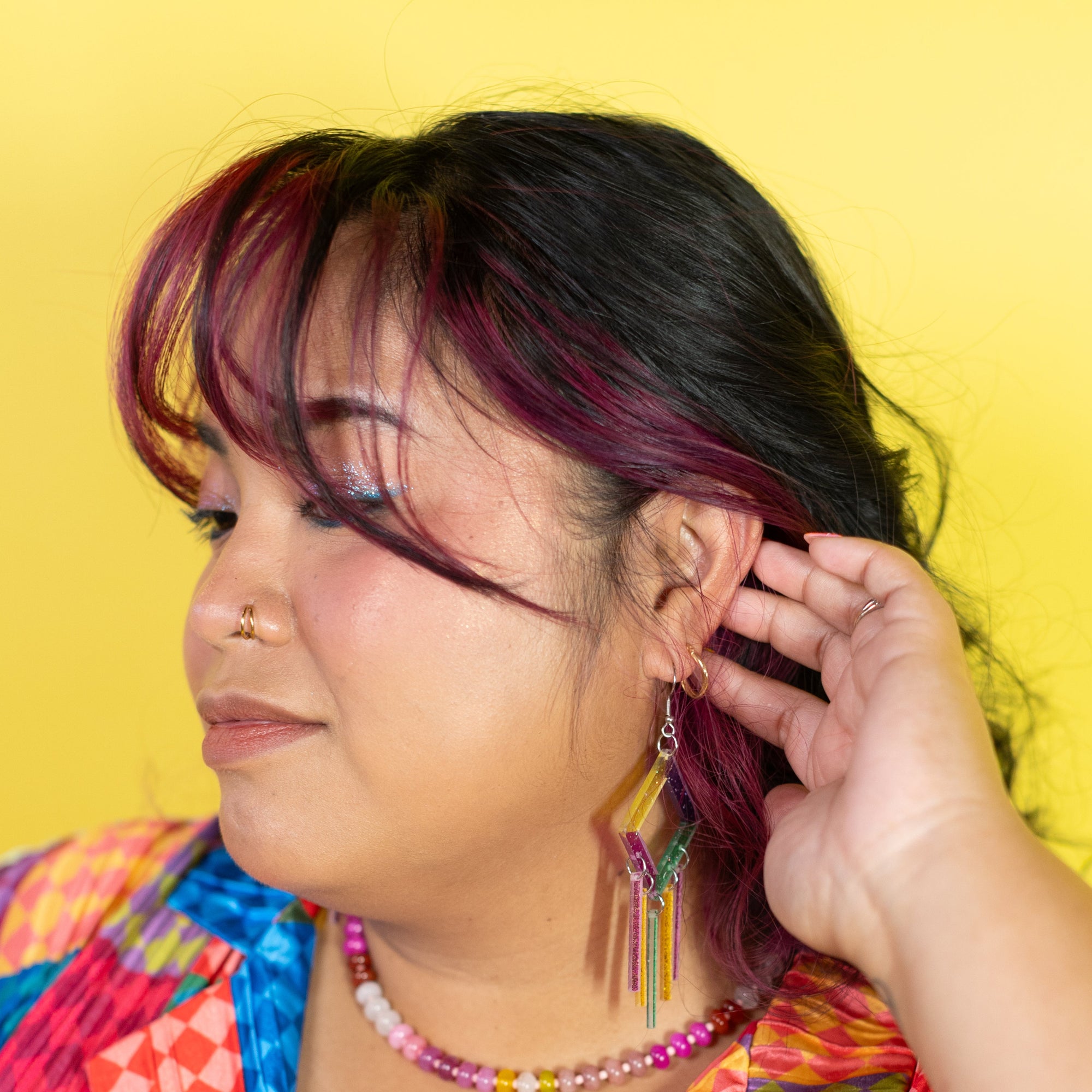 Woman wearing colorful earrings against a yellow background