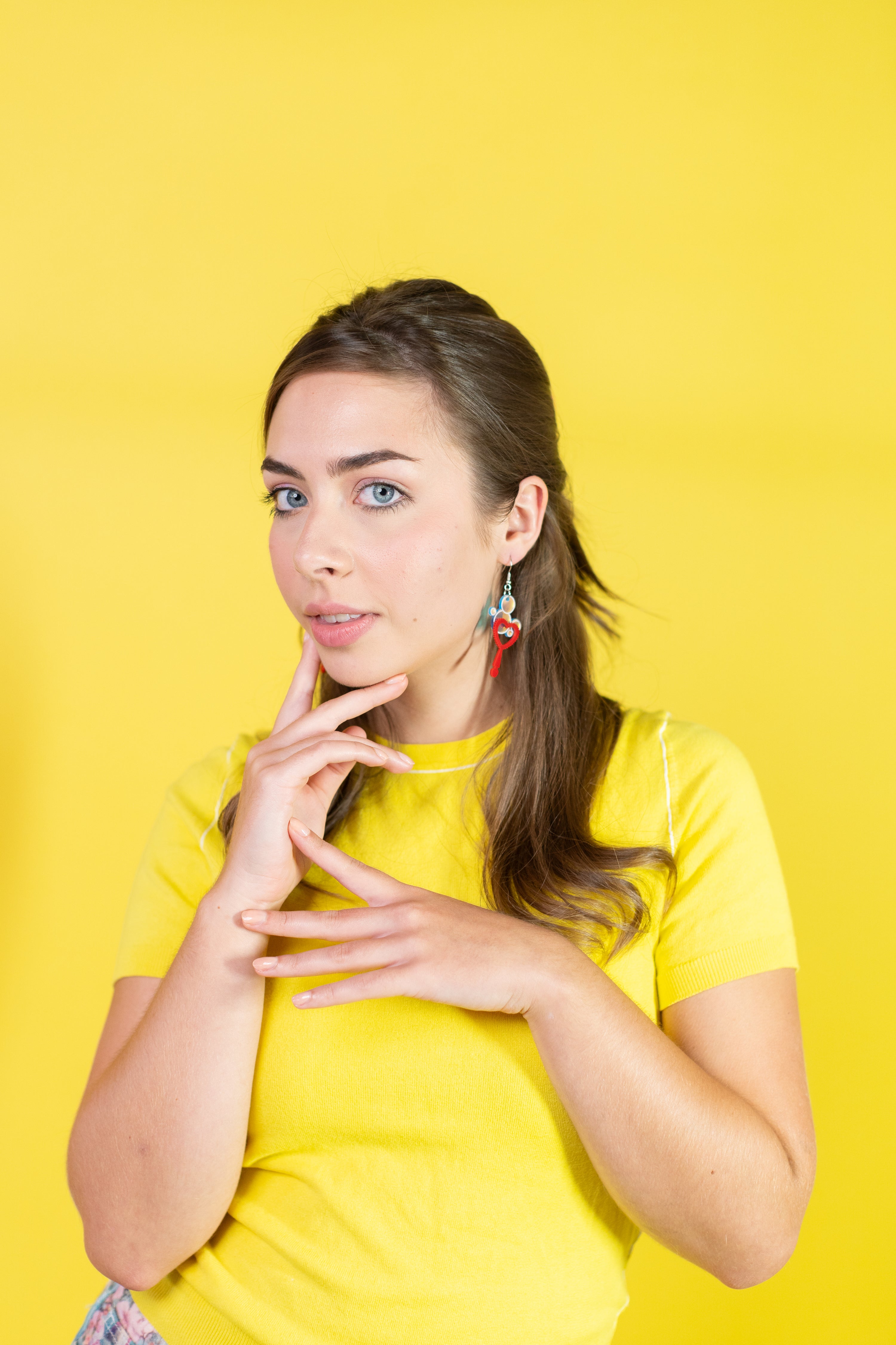 Woman in a yellow shirt posing with a thoughtful expression on a yellow background