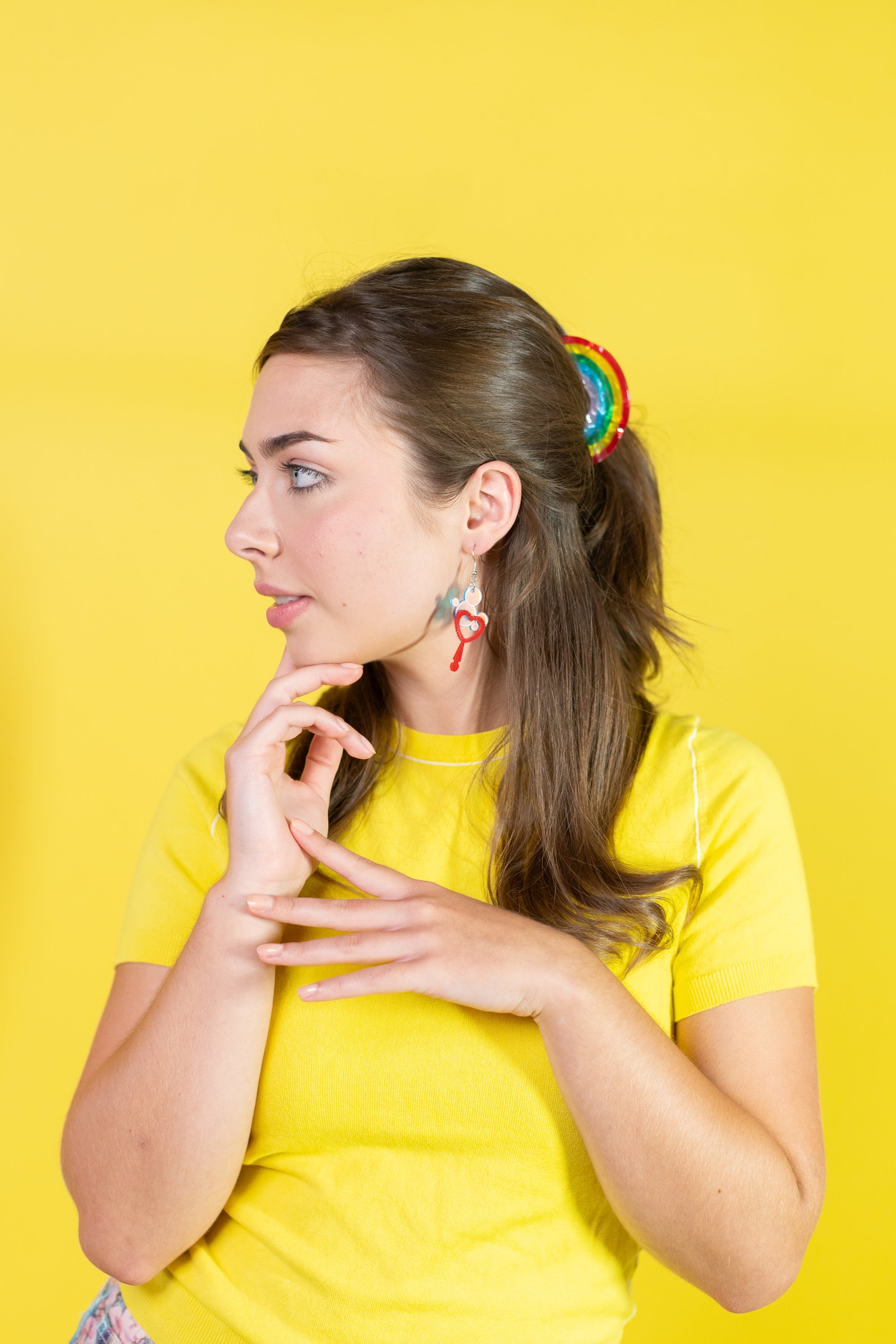 Woman in a yellow shirt with a colorful hair clip against a yellow background