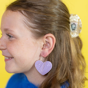 Girl wearing heart-shaped earrings with a yellow background