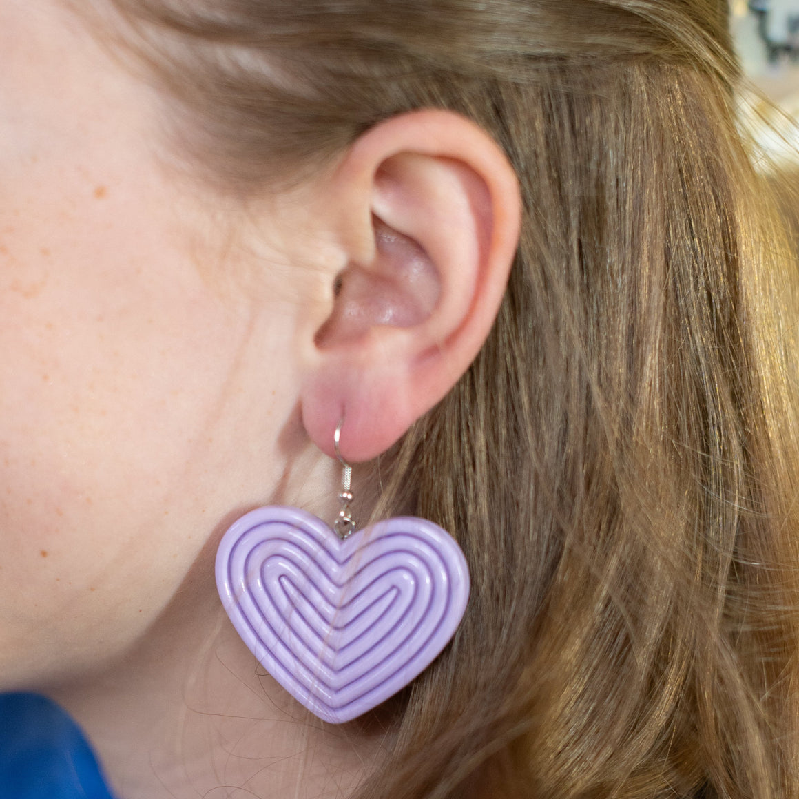 Girl wearing heart-shaped earrings with a yellow background
