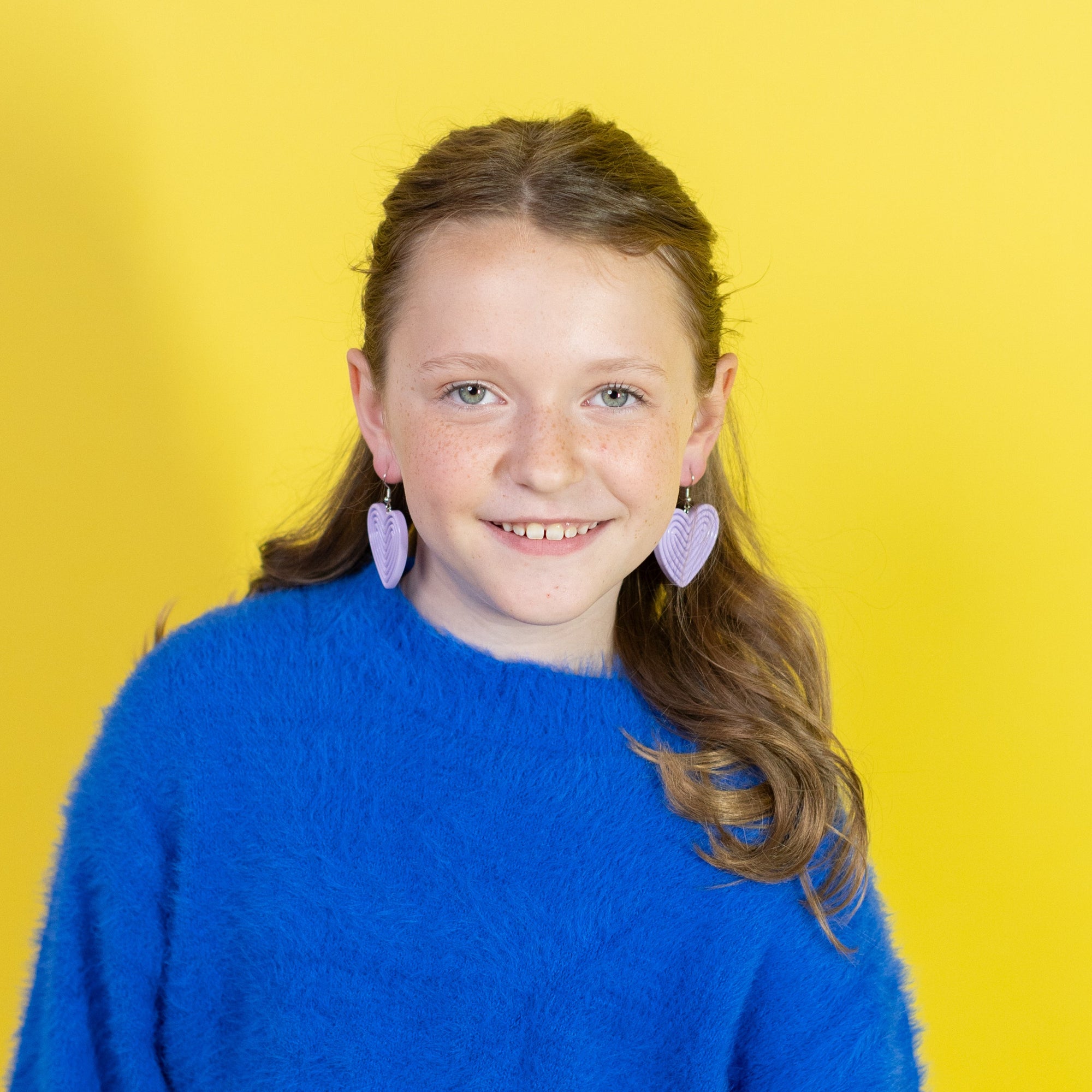 Young girl wearing a blue sweater and white skirt against a yellow background