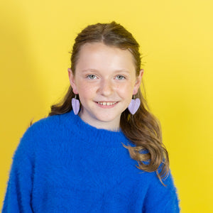 Young girl wearing a blue sweater and white skirt against a yellow background