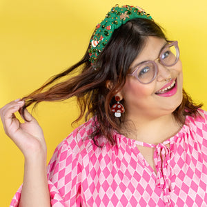 Woman in a pink patterned dress posing against a yellow background