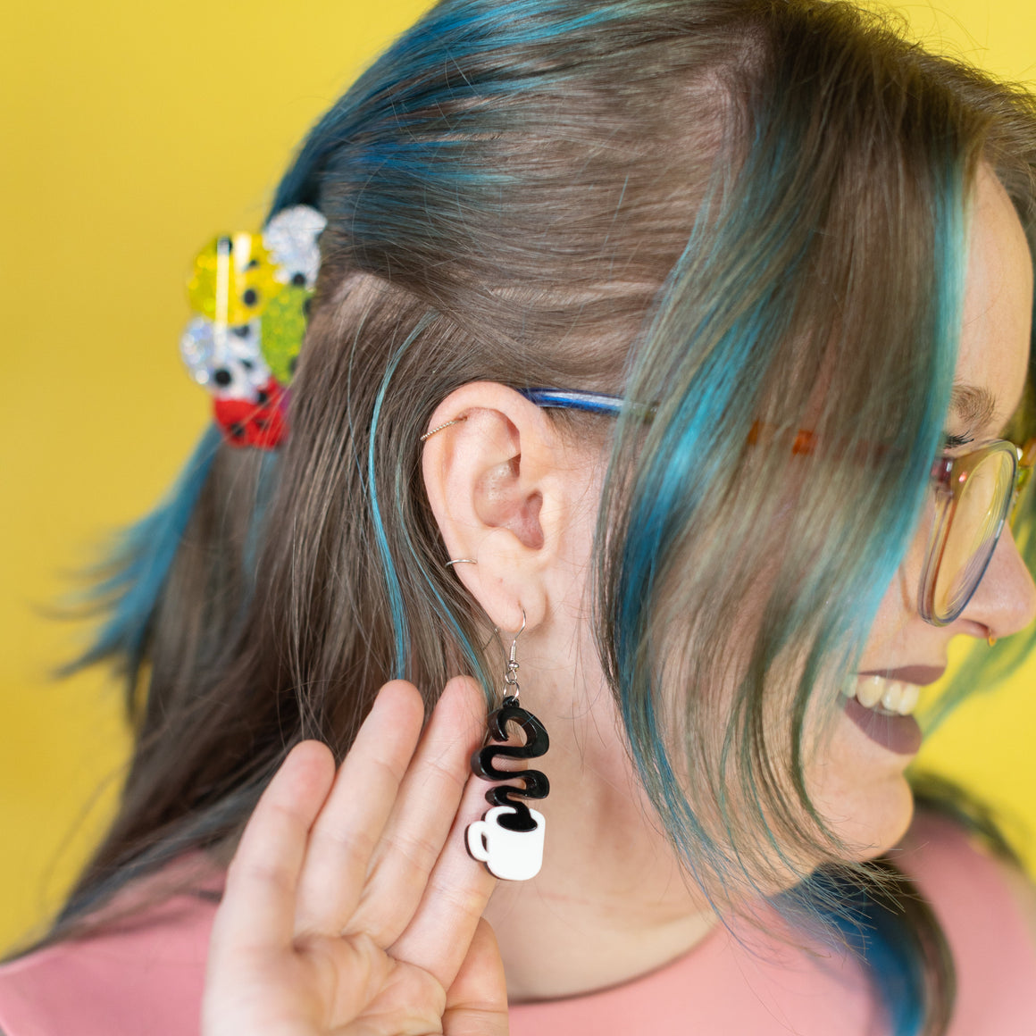 Person with colorful hair and accessories against a yellow background